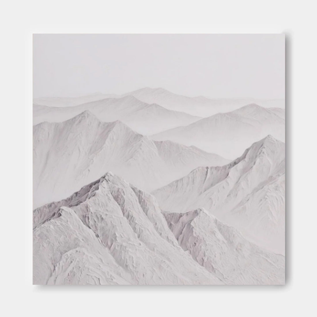 A serene landscape of snow-capped mountains, with their peaks gently rising against a hazy, pale blue sky.