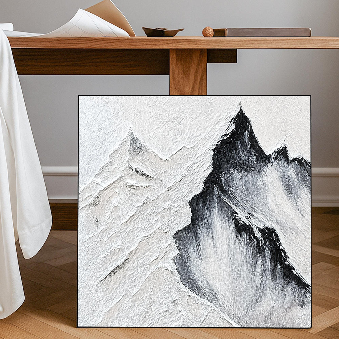 a striking black and white landscape featuring a dramatic mountain range with jagged peaks and a textured, rocky surface.